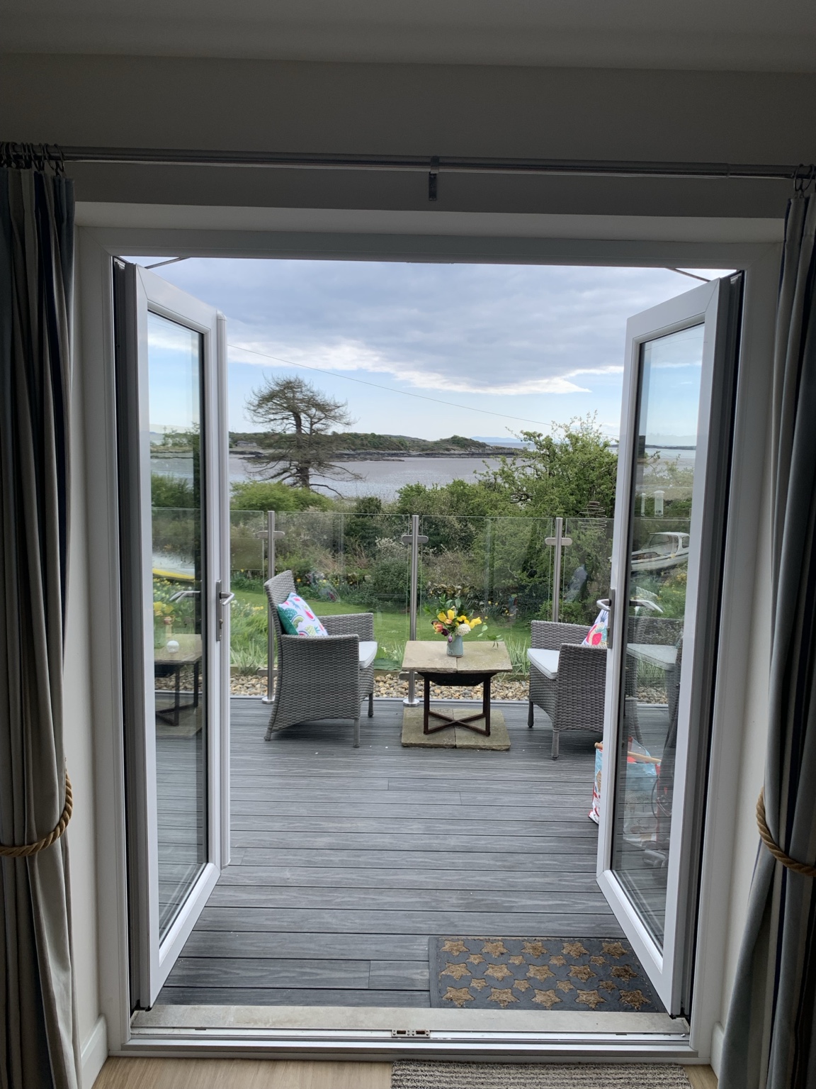 Open doors leading to The Boat House private deck with views across Fleet Bay