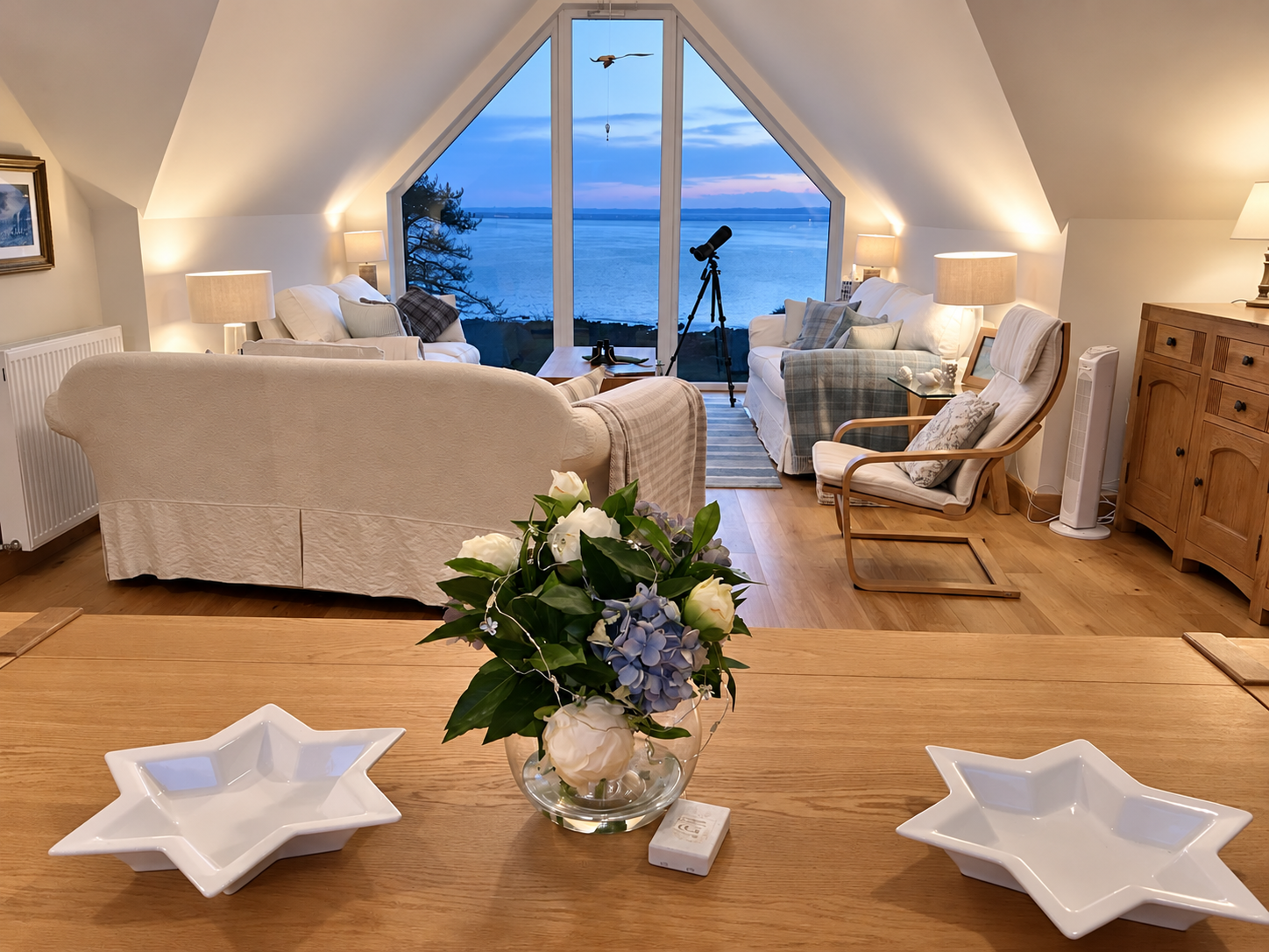 The Sunset Loft living room warmly lit at dusk with a blue view across Fleet Bay